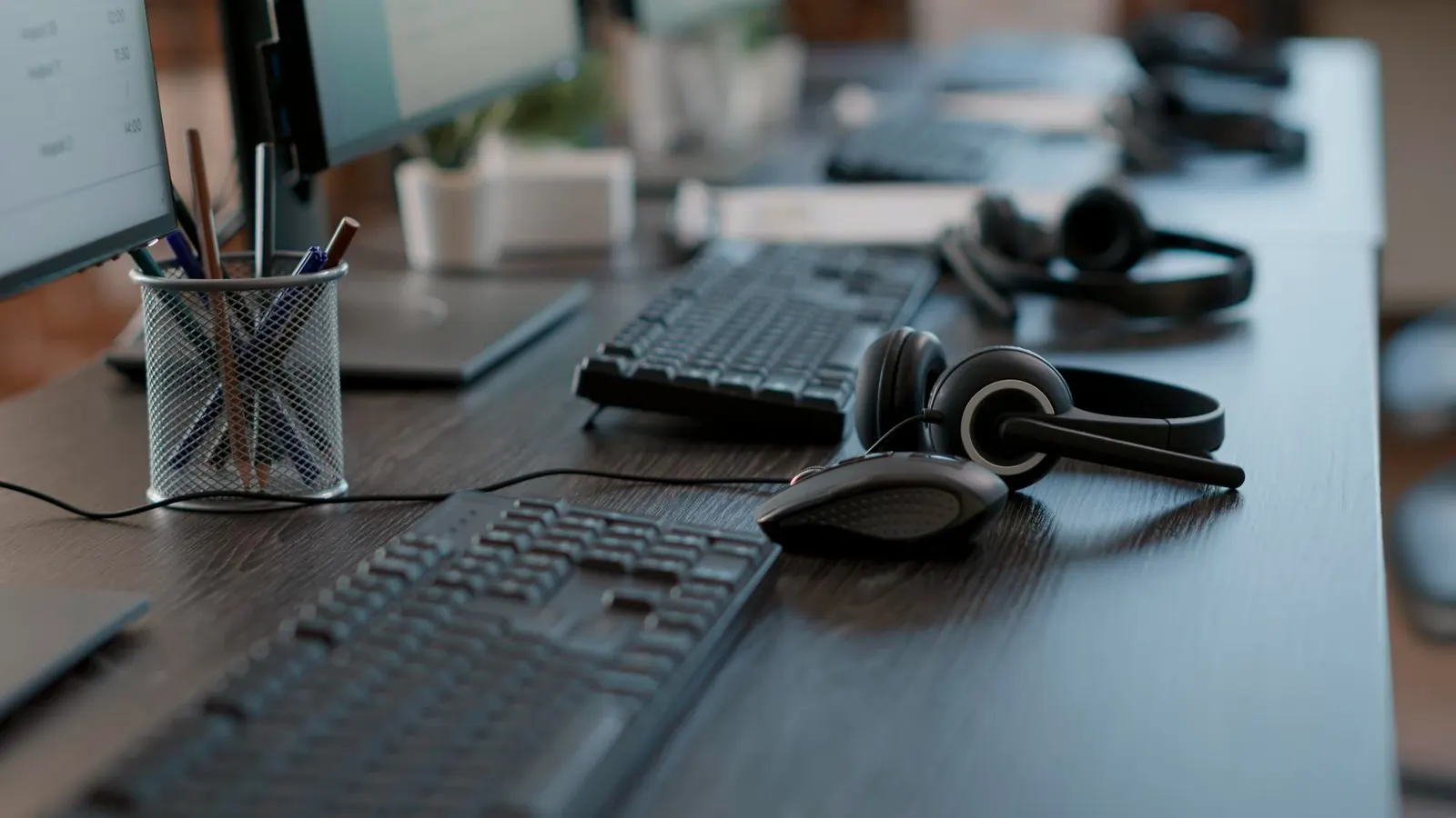 Empty office desks with keyboards and call headsets ready for an outbound calling session