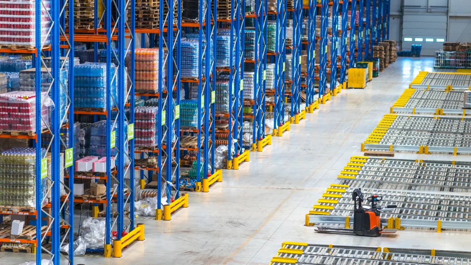Distribution warehouse with tall blue pallet racks, conveyor lanes and an electric pallet truck