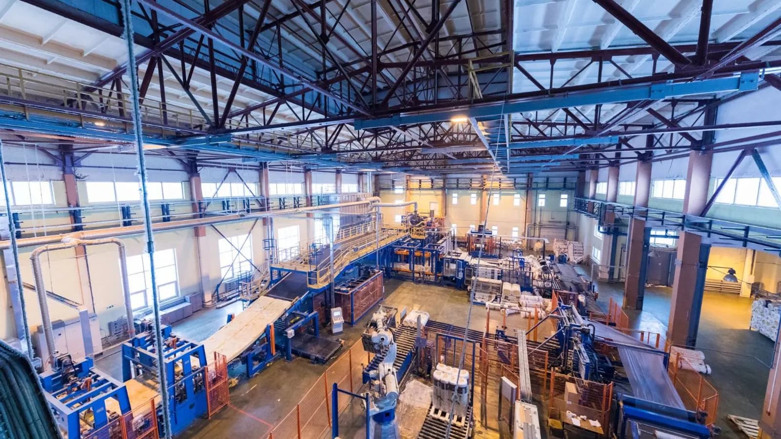 Wide view of a bright factory hall with production lines and machinery under a steel roof